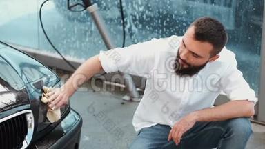 有胡子的男人在洗车场用布洗车